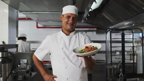 Portrait of mixed race male chef presenting dish and looking at camera