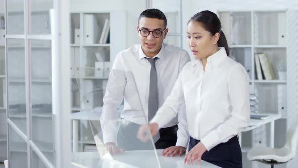 Two Young Professionals Using Transparent AR Touchscreen