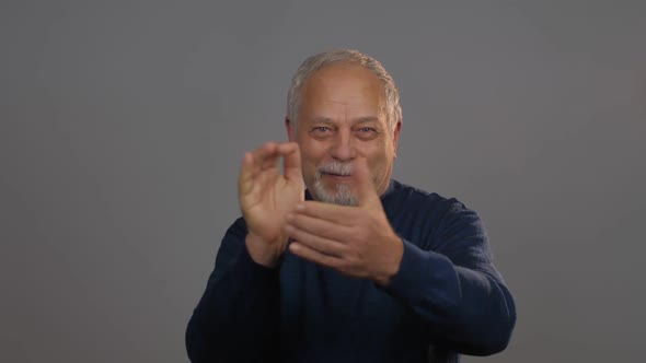 Glad Pensioner in Blue Pullover Claps Hands and Smiles