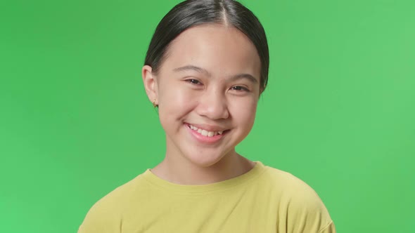 Smiling Young Asian Kid Girl Positively Shaking Her Head At The Camera In The Green Screen