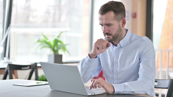 Sick Young Man with Laptop Coughing in Office