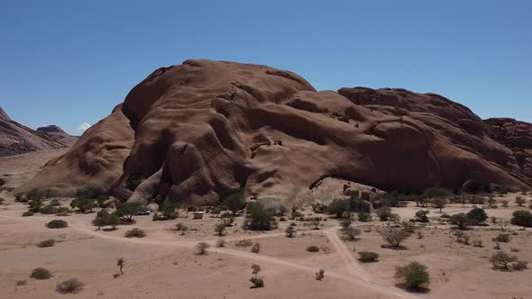 Huge round rock in the middle of the desert, small plants around, Erongo