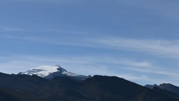 Time lapse of clouds moving over snow-capped mountain peak