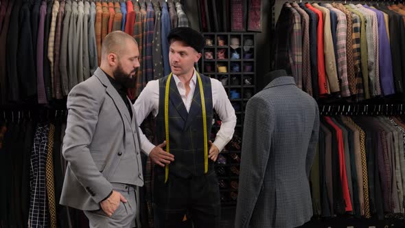 Slow motion of handsome man choosing a suit design with tailor in atelier