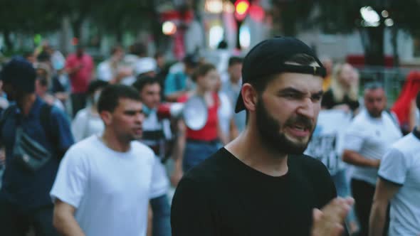 Political opposition male protester activist claps hands and marching in crowd.