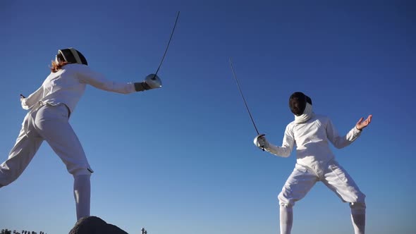 A man and woman fencing on the beach