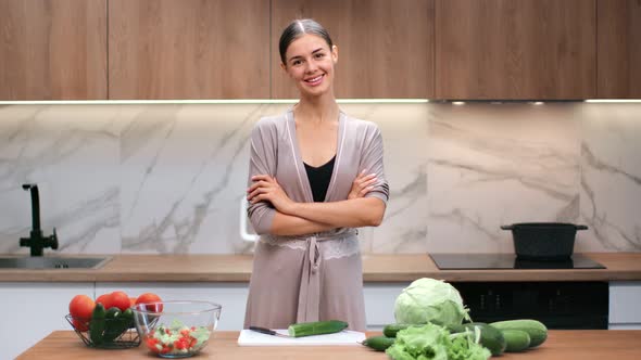 Adorable Housewife Posing at Kitchen with Table Full of Fresh Vegetables