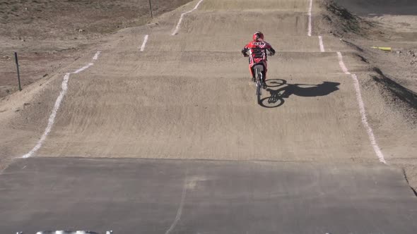 A young woman bmx rider riding on dirt track.