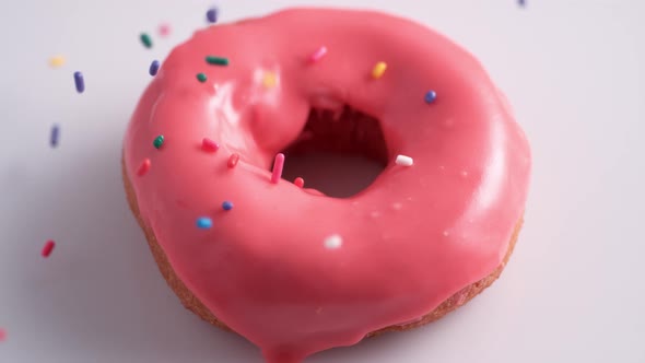 Sprinkling candy chocolate on frosted doughnut. Slow Motion. alt