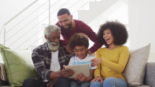 Multi-generation family laughing while using digital tablet at home