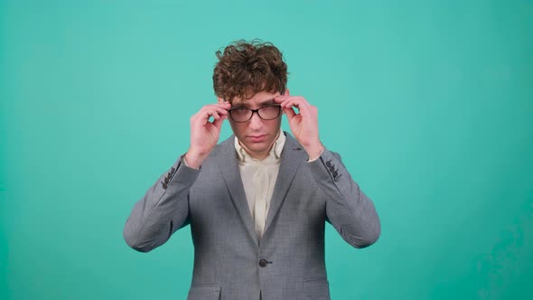Curly Haired Handsome Young Man That is Putting on Eye Glasses and Looking at Camera