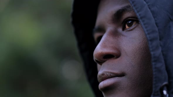 Thoughtful confident hooded young black african migrant-outdoor