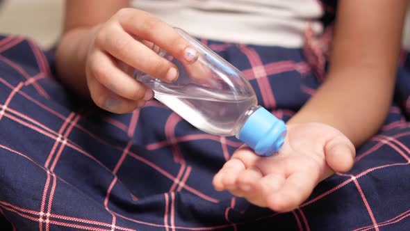 Child Hand Using Sanitizer Gel While Sited on Floor