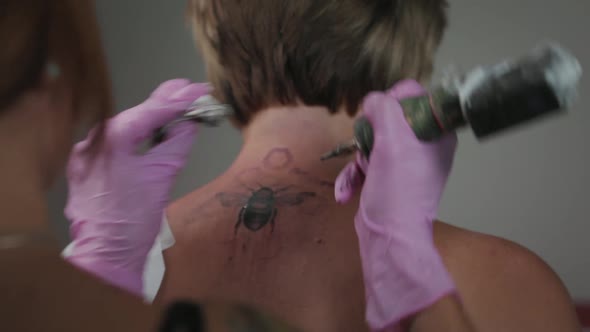 World tattoo day. Woman worker in pink gloves makes a tattoo to a client. Pan shot.