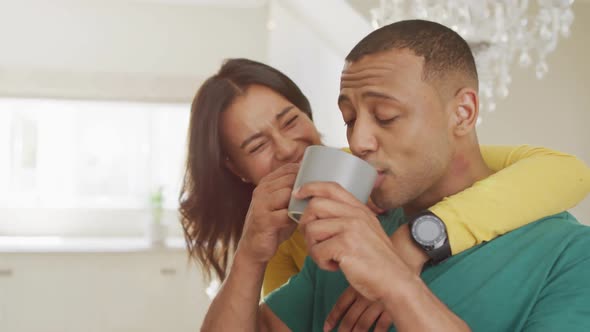 Happy biracial couple with coffee talking and embracing