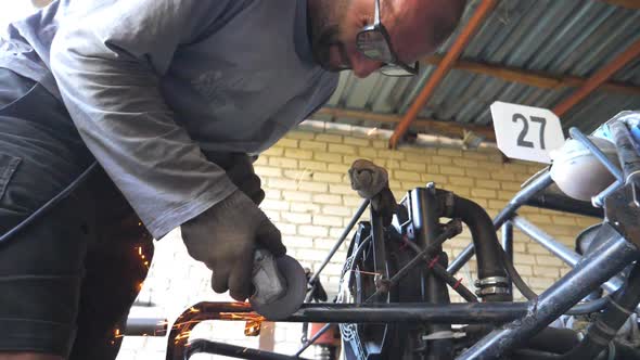 Adult Repairman or Mechanic Grinding Metal Using Circular Saw. Worker Cutting Some Automobile Detail