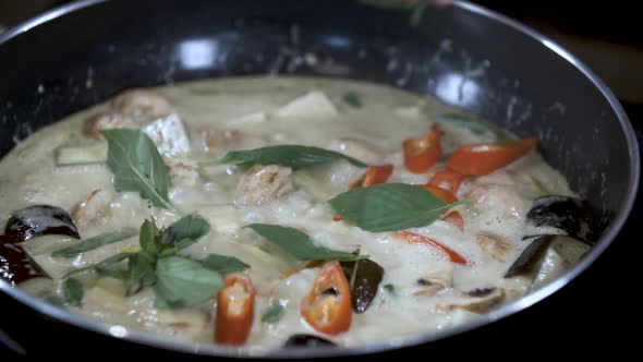 Adding Fresh Thai Basil on Simmering Healthy Vegan Vegatable Curry in Black Pan
