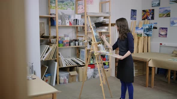 Woman Is Standing Near Easel and Drawing a Picture  General View of Workshop