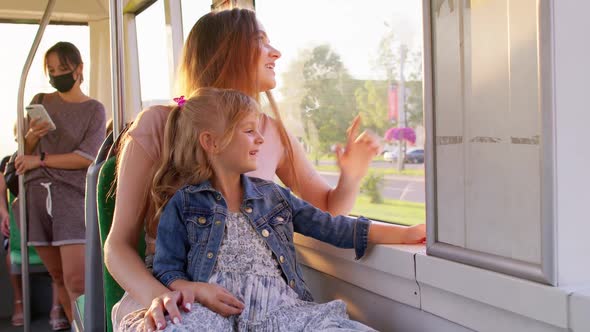 Family Rides in Public Transport Mother with Little Daughter Sit Together and Look Out Window Tram