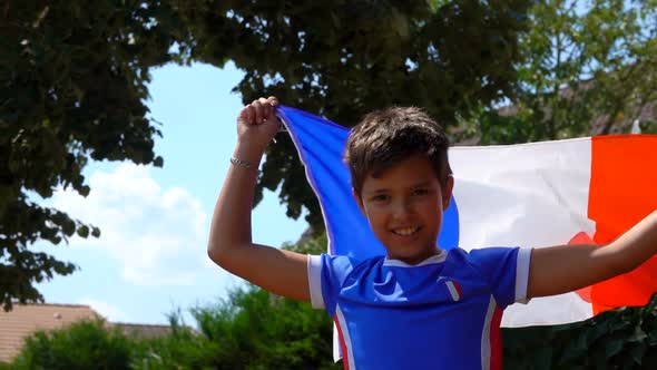 Boy Jumping Happily with a French Flag in His Hands