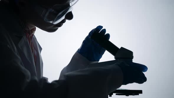 Virologist or Scientist is Looking Into Microscope alt