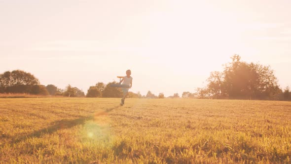 Little boy plays with a toy plane in a field at sunset. Childhood, freedom, inspiration concept.