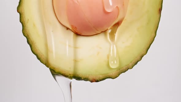 Macro Shot of Fresh Cut Avocado with Juice and Oil Stream on White Background