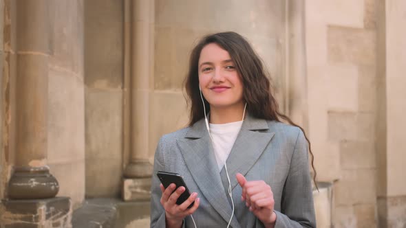 Woman in Headphones Earphones Listening to Music in the Street and Dancing