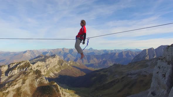 Aerial view of a man balancing while slacklining on a tightrope in the mountains.