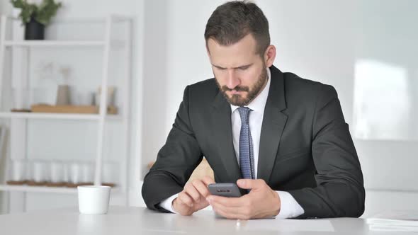 Tense Upset Businessman Reacting to Loss on Smartphone
