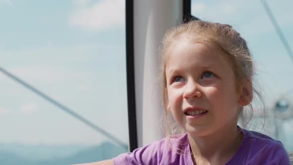 Thoughtful Girl Looks Up Riding Gondola of Safe Poma Lift