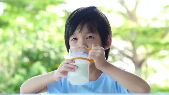 Cute Asian Child With A Glass Of Milk And Licking Lips