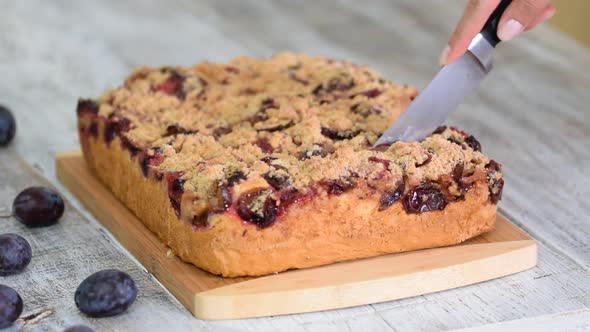 Woman Hand Cuts Crumble Plum Cake.