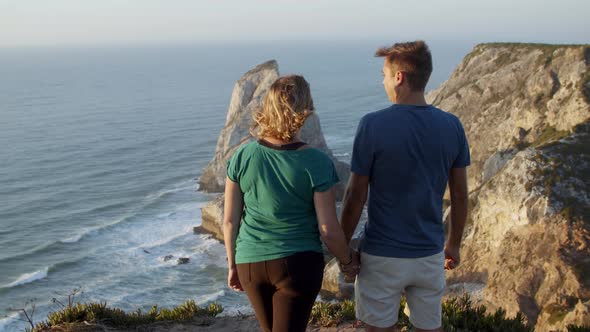 Romantic Couple Holding Hands Standing at Rocky Cliff