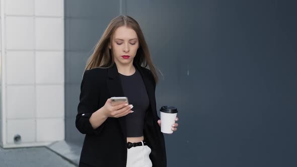 Business Woman Using Mobile Phone Typing Text Messages Holding Cup of Coffee