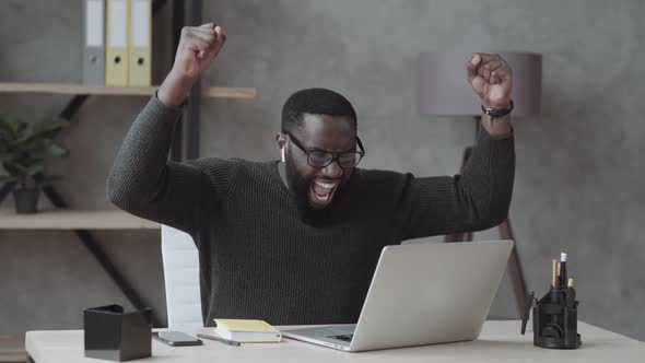 Overjoyed Black Male at Laptop Screen Rejoices in Winning on Online Bets, Excited African American