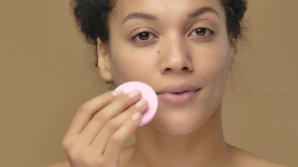 Beauty Portrait of Young African American Woman Cleansing Face with Pink Disc Removing Makeup