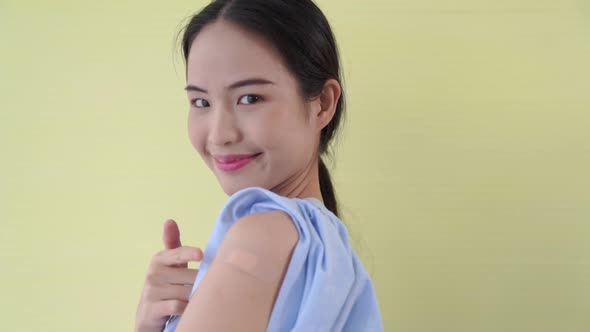 Young Asian Woman Showing COVID19 Vaccine Bandage Merrily