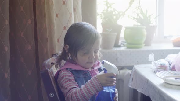 Little Girl Plays in the Kitchen with a Spray of Water Laughs and Rejoices