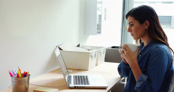 Female executive using laptop white having coffee