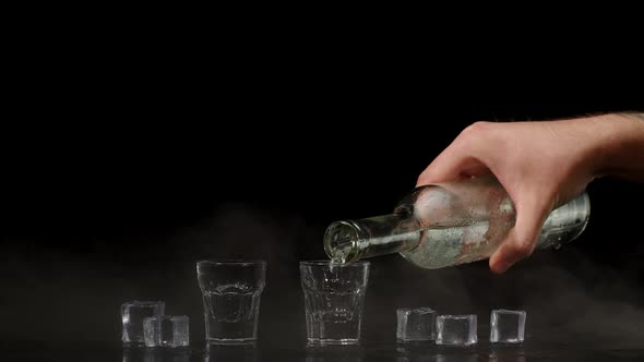 Two Hands with Glasses of Vodka Making Cheers Raising Toast on Black Background with Ice Cubes