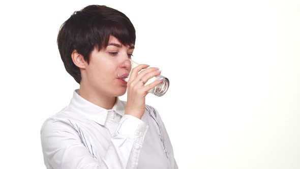 Confident Caucasian Lady Looking at Camera and Drinking Water From Glass Isolated Over White