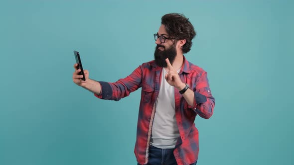 Portrait of a Bearded Man Talking on Video Call and Waving Hand Making Hi Gesture.