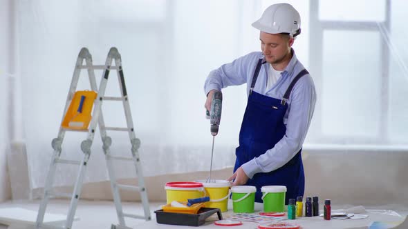 Male Construction Specialist Mixes Electric Construction Mixer Paint Color for Wall Painting Making