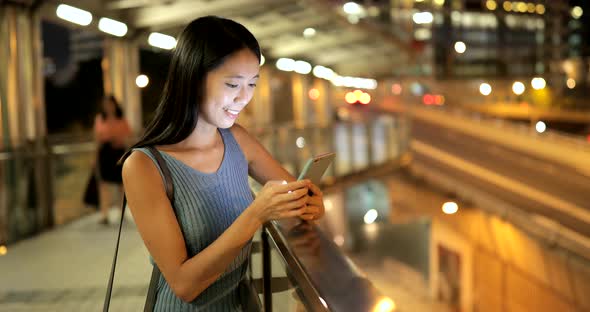 Woman using mobile phone in the city at night 