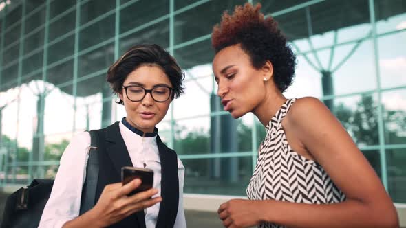 Colleagues Looking at Phone Speaking Smiling Business Centre Background