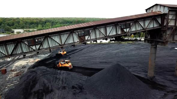 Bulldozer pushing coal on enormous coal pile. Extractive industry. Aerial view.