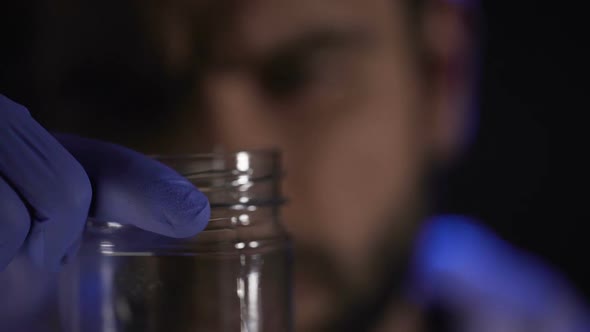 Forensic Scientist Setting Stub of Cigar Into Glass Jar, Searching for Evidence