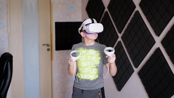 Teenager in 3D Glasses with Game Controllers Plays in a Soundproof Room