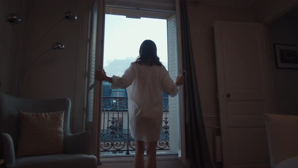 Attractive woman opening the door to the balcony with a view